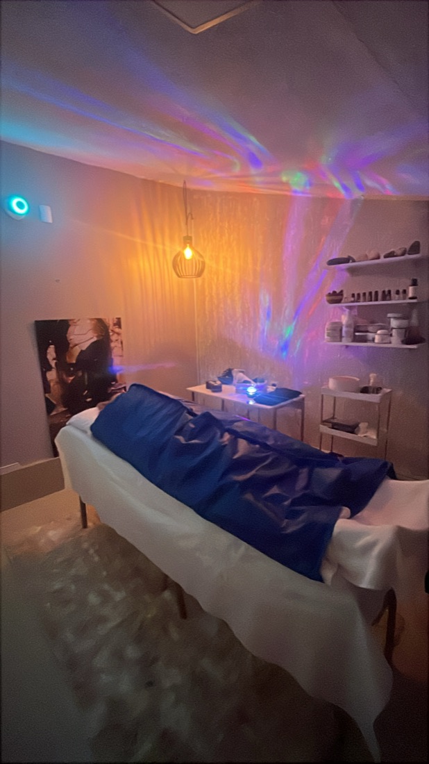 Sala de atendimento do Le Bain com maca, prateleira de produtos e luz colorida